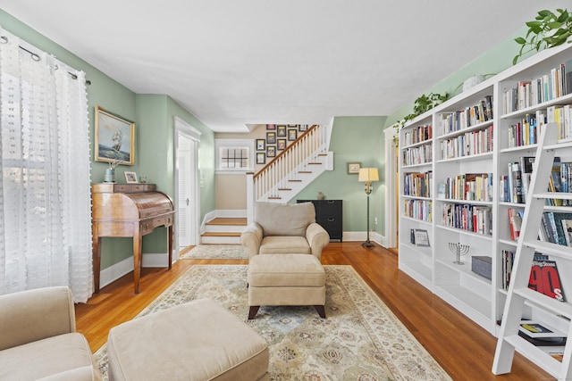 sitting room with stairway, baseboards, and wood finished floors