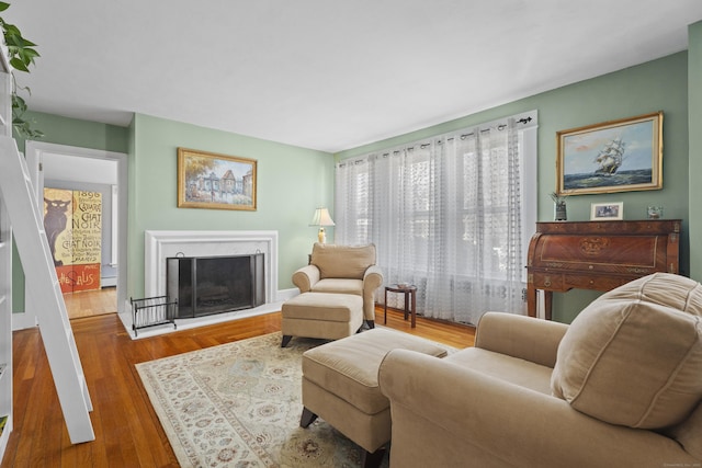 living area with a fireplace, a baseboard heating unit, and wood finished floors