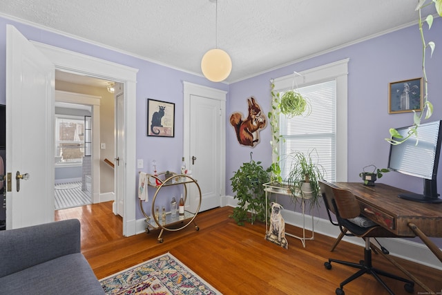 office area with a healthy amount of sunlight, ornamental molding, and wood finished floors