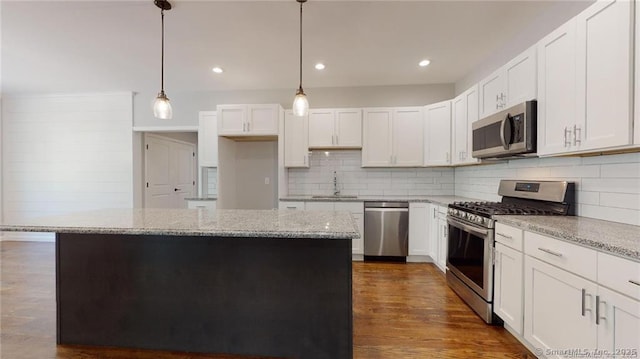 kitchen with a kitchen island, dark wood-style flooring, a sink, stainless steel appliances, and white cabinetry