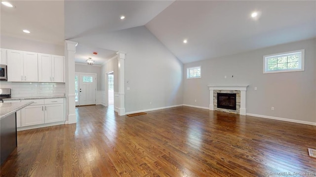 unfurnished living room with baseboards, dark wood finished floors, decorative columns, recessed lighting, and a fireplace