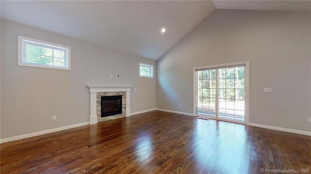 unfurnished living room featuring baseboards, high vaulted ceiling, wood finished floors, and a fireplace