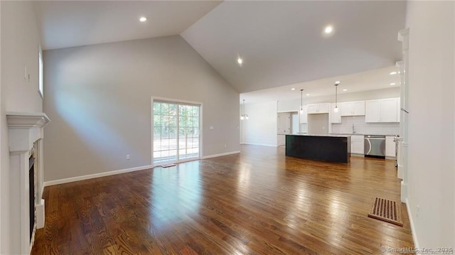 unfurnished living room with visible vents, high vaulted ceiling, dark wood-style floors, and a fireplace