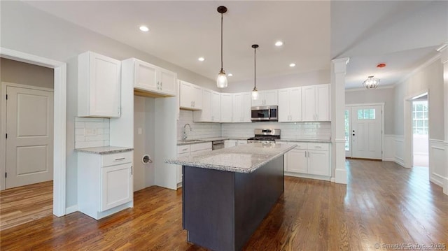 kitchen with a kitchen island, light stone countertops, stainless steel appliances, dark wood-style floors, and white cabinetry