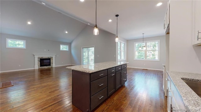 kitchen with a stone fireplace, dark wood finished floors, white cabinetry, and a healthy amount of sunlight