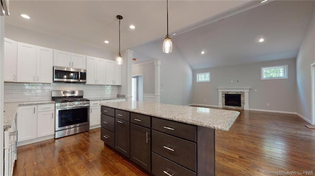 kitchen featuring dark wood-type flooring, appliances with stainless steel finishes, white cabinets, and a fireplace