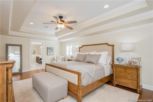 bedroom with a tray ceiling, baseboards, wood finished floors, and crown molding