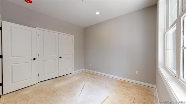 unfurnished bedroom with recessed lighting, a closet, and baseboards