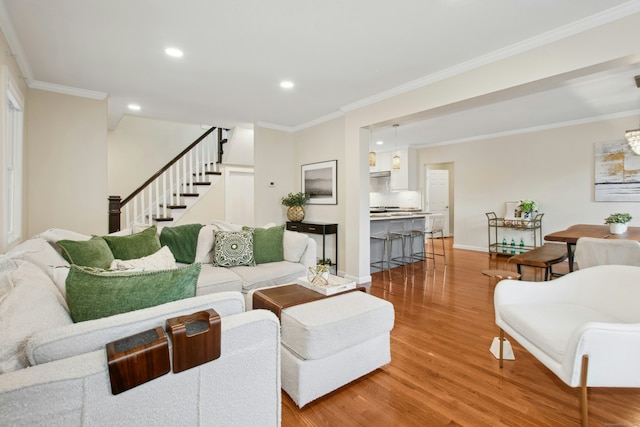 living area featuring light wood finished floors, baseboards, ornamental molding, stairs, and recessed lighting