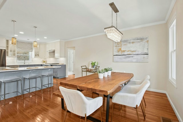 dining room with visible vents, crown molding, baseboards, and wood finished floors