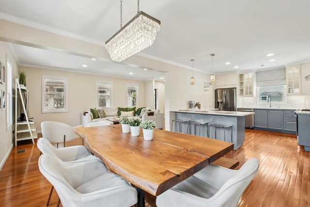 dining area featuring light wood-style flooring, a chandelier, crown molding, and recessed lighting