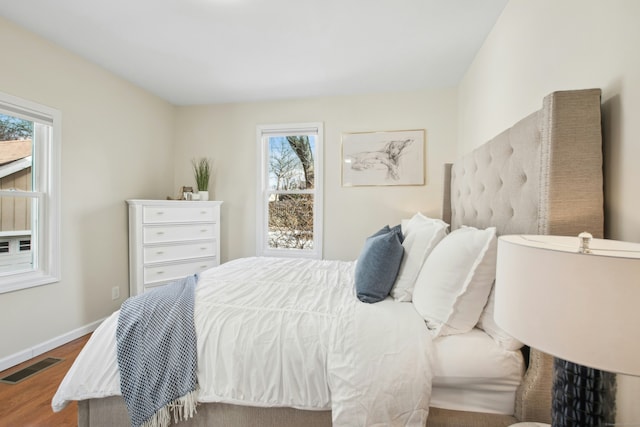 bedroom featuring visible vents, baseboards, and wood finished floors