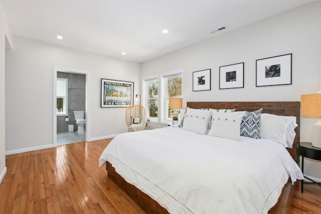 bedroom with hardwood / wood-style flooring, recessed lighting, visible vents, baseboards, and ensuite bath