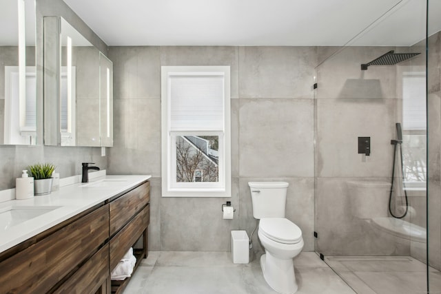 full bath featuring toilet, a sink, tile walls, double vanity, and walk in shower