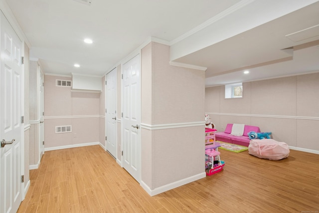 recreation room with baseboards, visible vents, crown molding, and wood finished floors