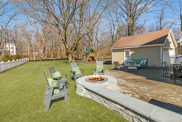 view of yard with a patio, a playground, an outdoor structure, fence, and an outdoor living space with a fire pit