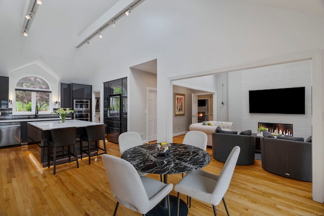 16 Whitehall Pl, Farmington, CT 06032 - dining space with light wood-style flooring, a large fireplace, track lighting, and vaulted ceiling