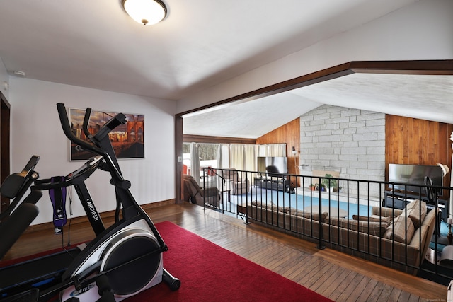 workout room with hardwood / wood-style flooring, wooden walls, and lofted ceiling