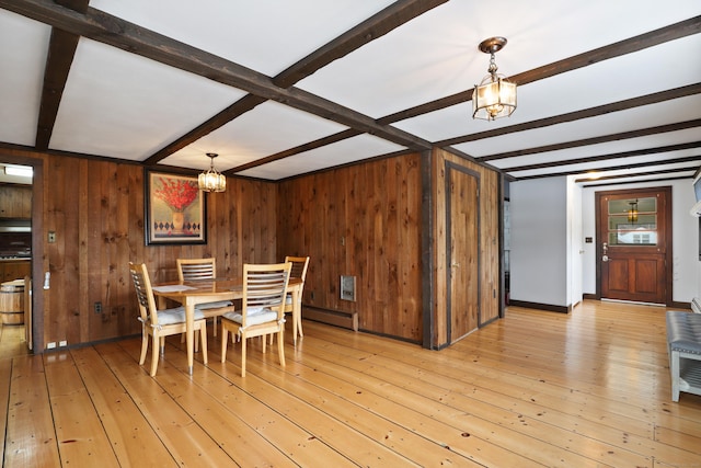 dining space with beamed ceiling, a notable chandelier, and light hardwood / wood-style floors