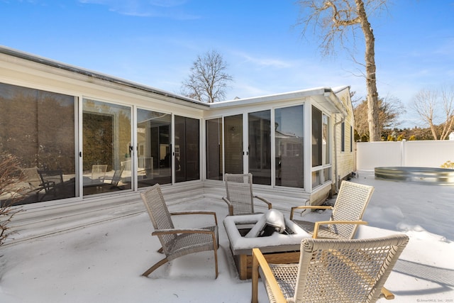 view of patio / terrace featuring fence, a sunroom, and a hot tub