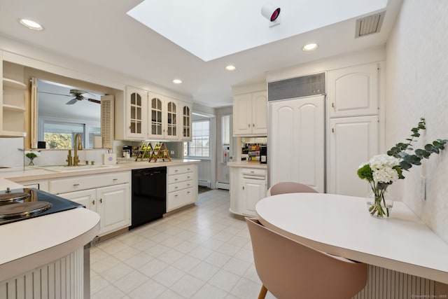 kitchen with black dishwasher, glass insert cabinets, light countertops, and a sink