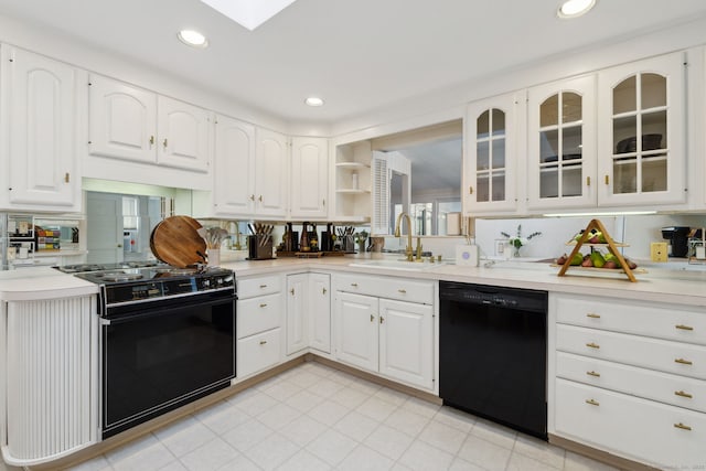 kitchen with a sink, black appliances, white cabinets, and light countertops