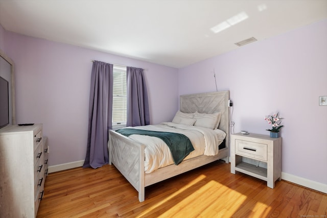 bedroom featuring light wood-type flooring, baseboards, and visible vents