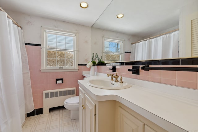 bathroom featuring toilet, recessed lighting, tile walls, vanity, and radiator