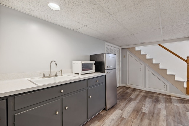 kitchen with white microwave, a sink, light countertops, gray cabinets, and freestanding refrigerator