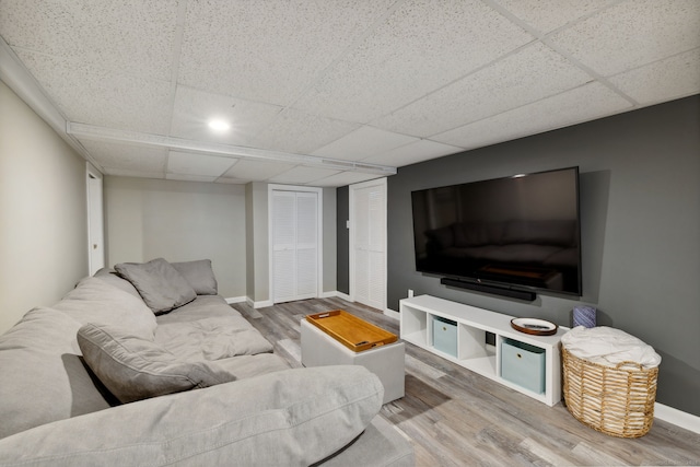 living area with a drop ceiling, baseboards, and wood finished floors