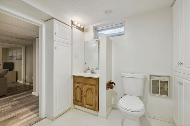 half bathroom featuring a textured ceiling, toilet, visible vents, vanity, and baseboards