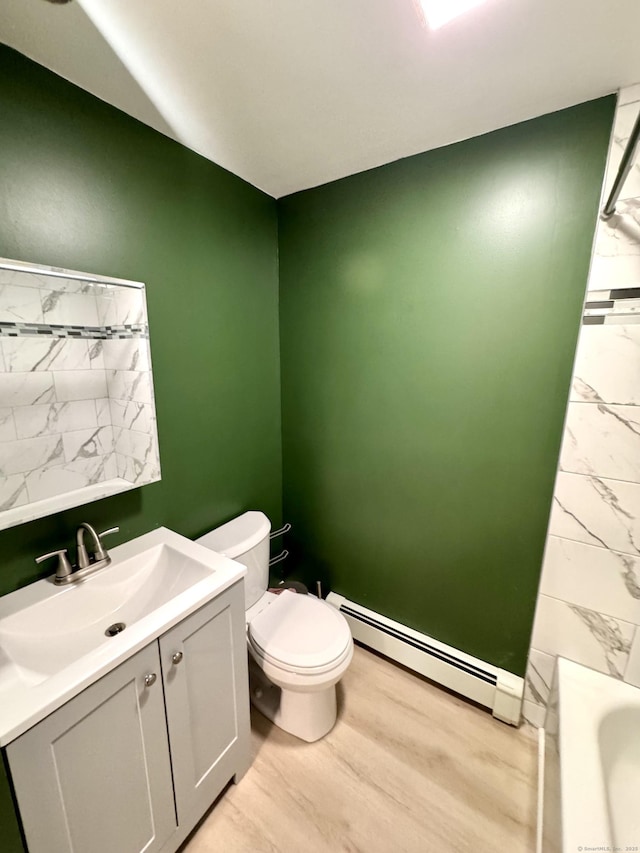 bathroom with a baseboard heating unit, wood finished floors, vanity, and toilet