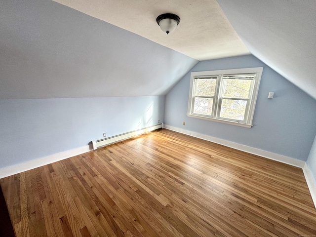 bonus room with light wood finished floors, a baseboard radiator, baseboards, and vaulted ceiling