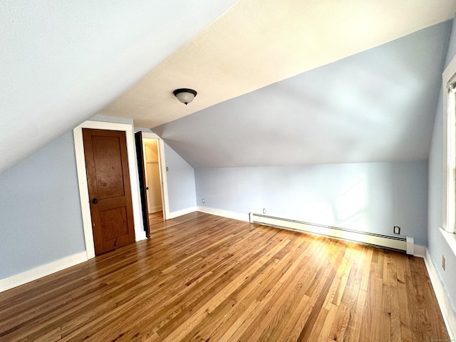 bonus room with a baseboard heating unit, wood finished floors, and baseboards