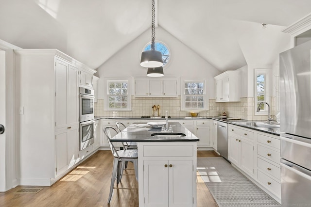 kitchen featuring dark countertops, light wood-style flooring, stainless steel appliances, and a sink