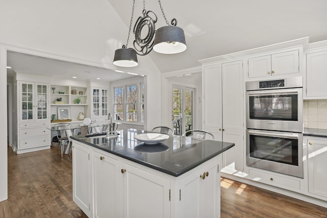 kitchen featuring vaulted ceiling, double oven, dark countertops, and white cabinets