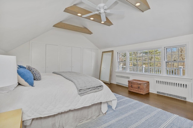 bedroom with wood finished floors, radiator, vaulted ceiling with beams, and two closets