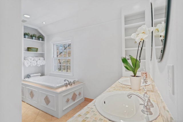 bathroom featuring lofted ceiling, tile patterned flooring, a sink, and a garden tub