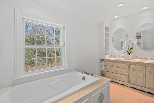 bathroom with double vanity, a garden tub, a sink, and recessed lighting