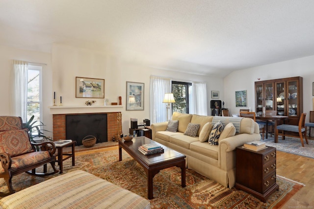 living room featuring a fireplace, vaulted ceiling, and wood finished floors