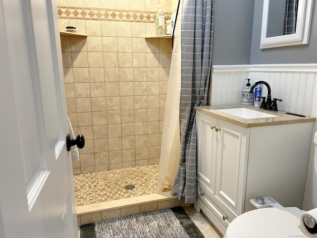 full bath featuring a stall shower, wainscoting, toilet, tile patterned flooring, and vanity