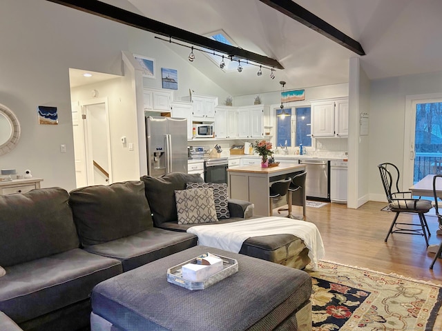 living room featuring baseboards, light wood-style flooring, high vaulted ceiling, and beam ceiling