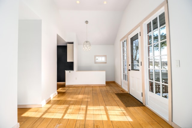 foyer with light wood-style floors, vaulted ceiling, baseboards, and an inviting chandelier