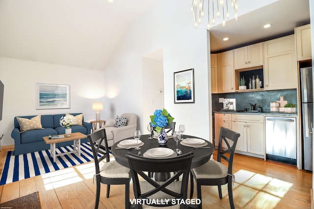 dining space with vaulted ceiling, recessed lighting, light wood-style flooring, and an inviting chandelier