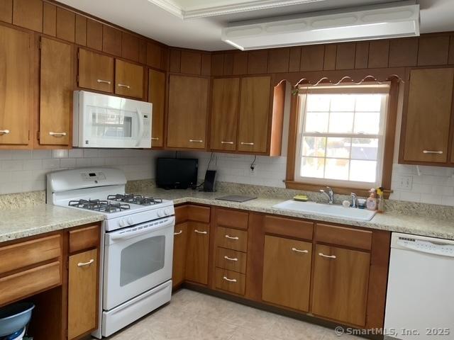 kitchen with sink, white appliances, and decorative backsplash