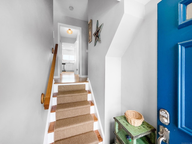 staircase featuring baseboards and wood finished floors