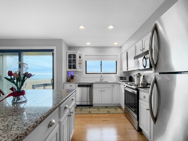 kitchen with white cabinets, a sink, stainless steel appliances, and light wood-style floors