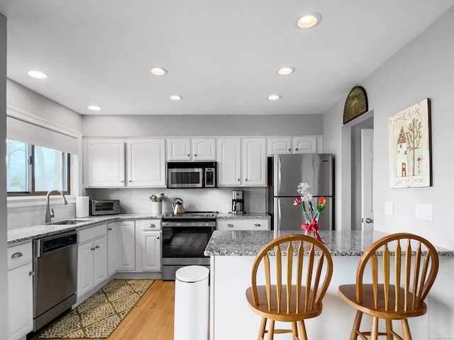 kitchen featuring backsplash, a sink, stainless steel appliances, and a breakfast bar