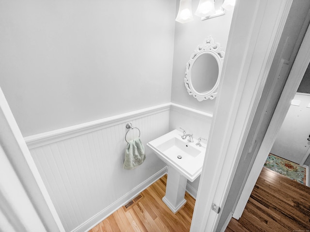 bathroom with a wainscoted wall, visible vents, and wood finished floors