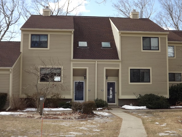 townhome / multi-family property featuring a chimney and a shingled roof
